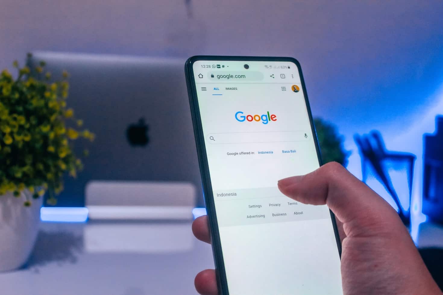 Hand holding a smartphone open to the Google homepage, illustrating google search tips for better results